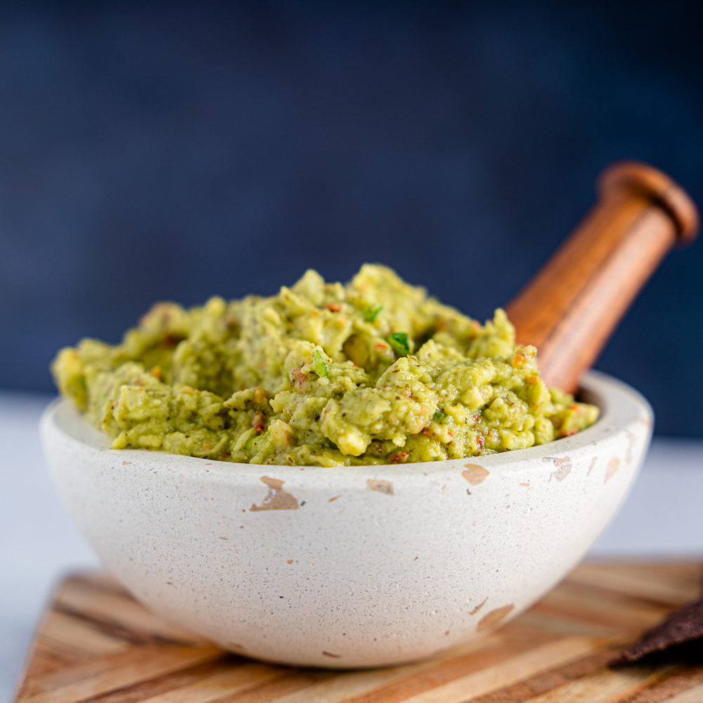Green Guacamole pilled high in a stoneware bowl