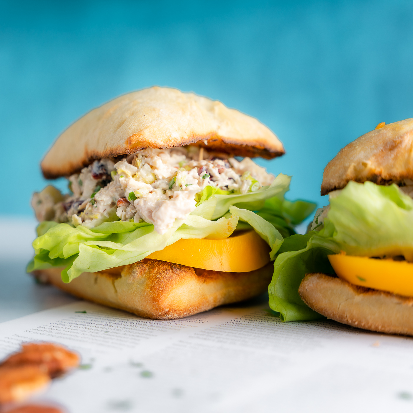 Chicken Salad Sandwich with a thick yellow tomato slice with a blue back drop