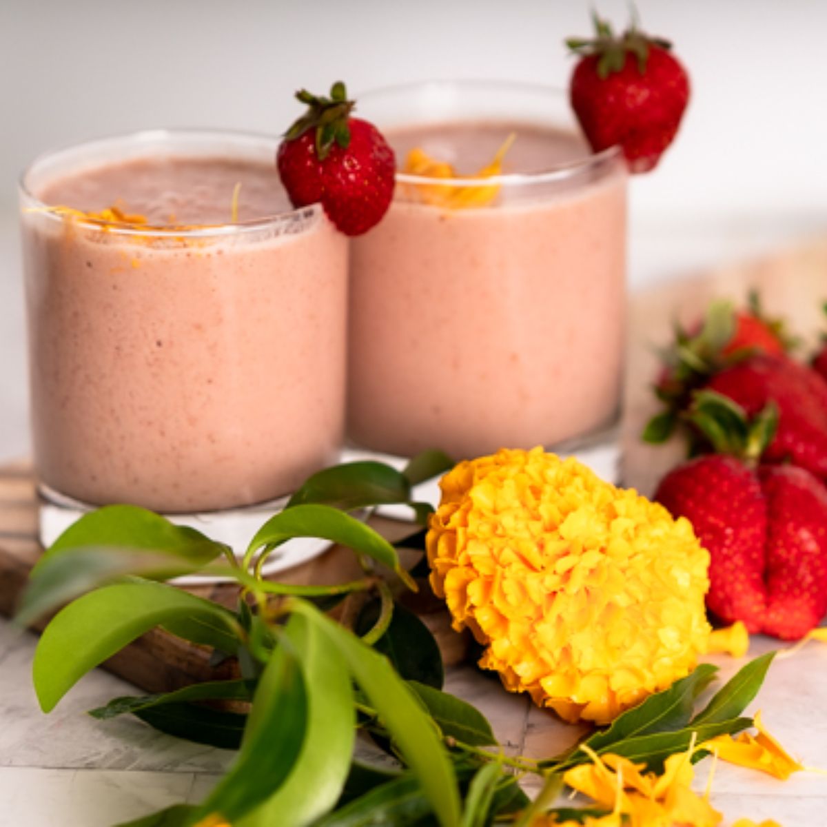 Panera Strawberry Banana Smoothie Recipe Copycat in two short glasses with a strawberry garnish and spring flowers props
