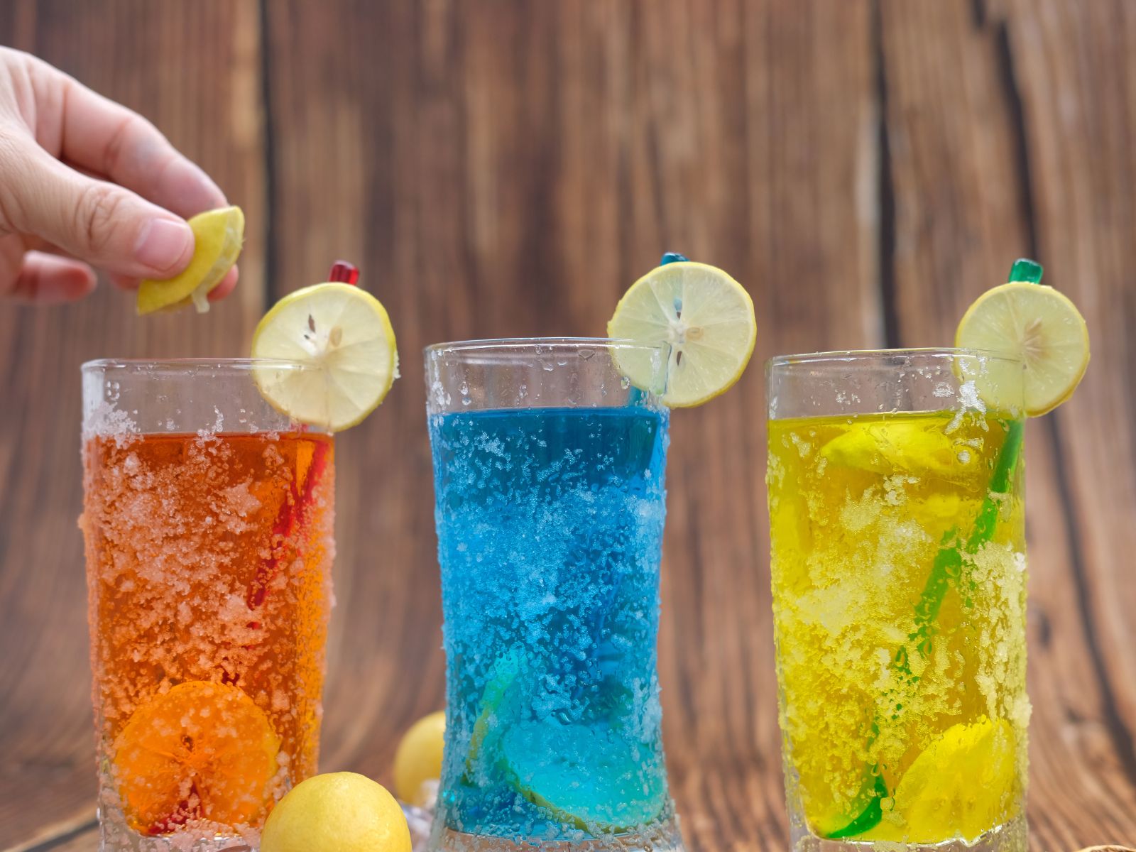 Three mocktails of different colors (orange, blue, and yellow). 