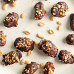 Snickers Dates on a plate with peanuts scattered.