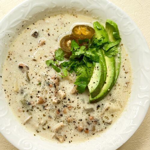 Creamy Blue Oyster Mushroom Chowder top down view with a garnish of avocado, herbs, and sliced jalapeno.