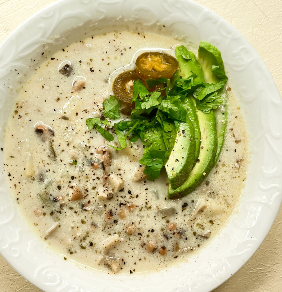Creamy Blue Oyster Mushroom Chowder top down view with a garnish of avocado, herbs, and sliced jalapeno. 