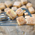 Baked Tofu on a fish spatula hovering above a baking sheet with more Crispy Baked Tofu