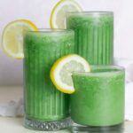 3 glasses of green juice smoothie with a white napkin and pick background
