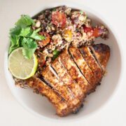 Southwest Bowl with quinoa and grilled southwest chicken breast in a white bowl with herb and lime garnish