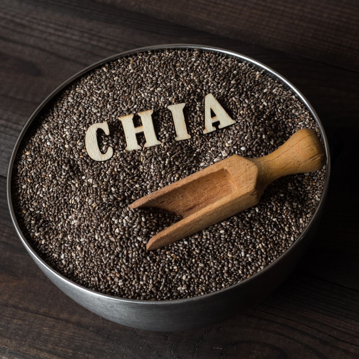 Chia seeds in a black bowl. Words are inside the bowl spelling out Chia. 