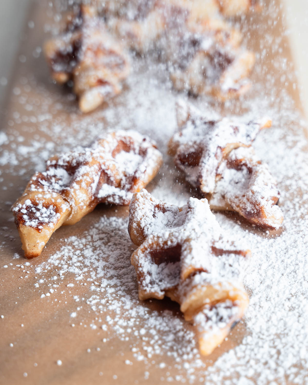 Croffles with a dusting of powdered sugar on a parchment paper lined cutting board. 