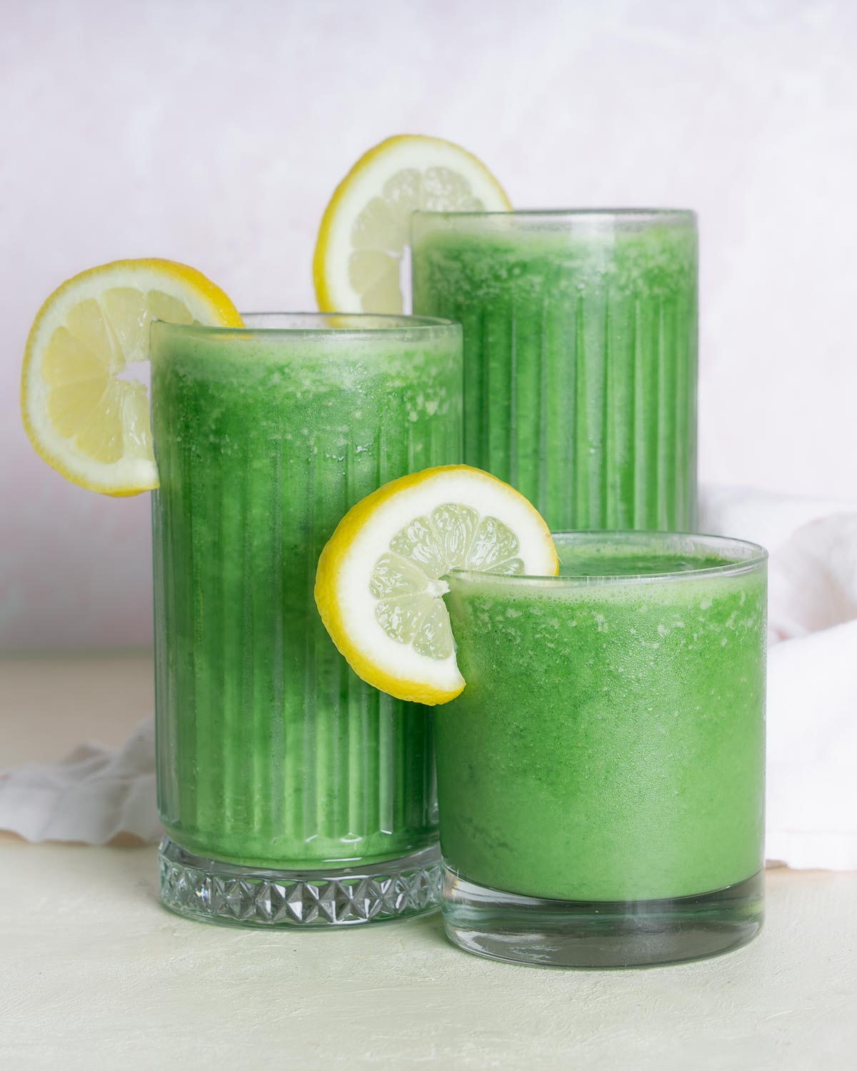 Green Morning Juice Smoothie with 3 classes of carrying heights. Garnished with a lemon slice.