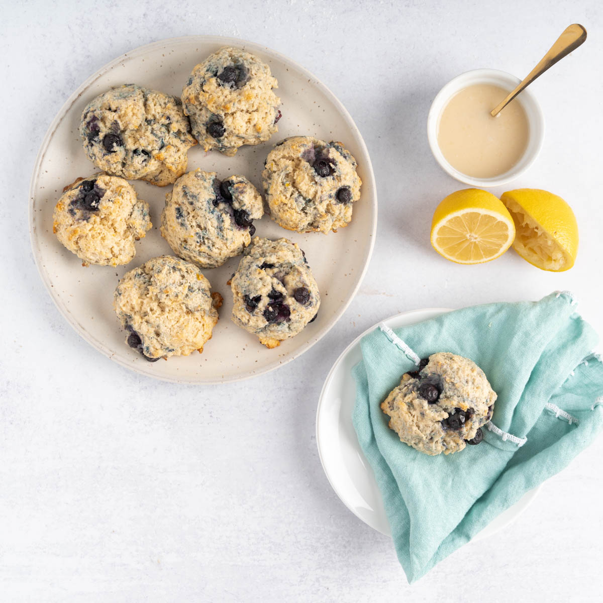 Blueberry Biscuits sered on a plate with the sweet lemon glaze of to the side in a white bowl
