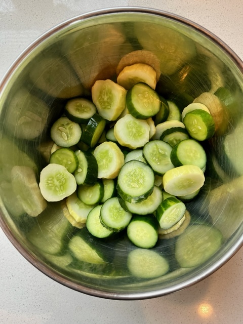 sliced salted cucumbers in metal bowl