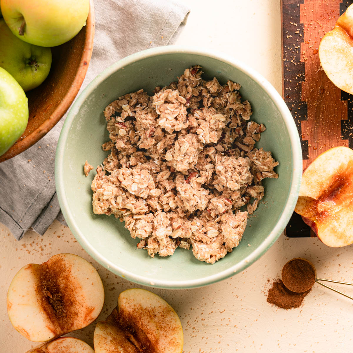 Oat Pecan Topping with apples and cinnamon surrounding the topping bowl.