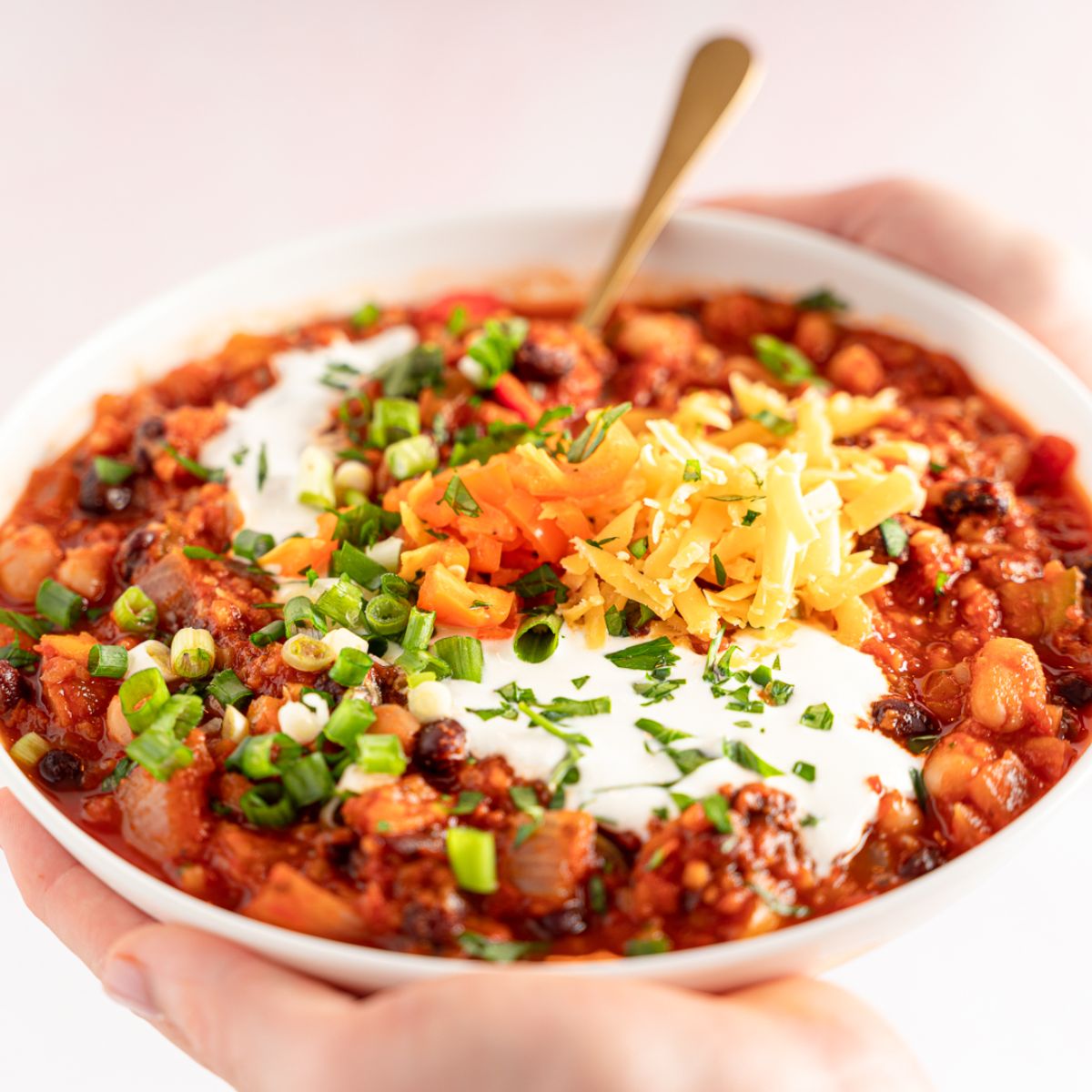 A big bowl of Vegan Vegetable Chili enclosed in two hands in a white bowl.