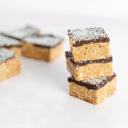three chocolate peanut butter crunch bars stacked with more bars in the background