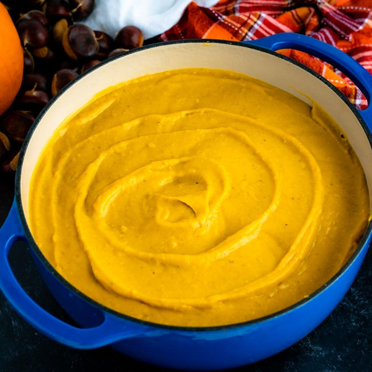 Blue soup pot filled with a swirled orange-gold pumpkin chestnut soup