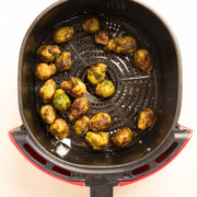 Golden Brown Air Fryer Brussels Sprouts in a red Air Fryer Basket.