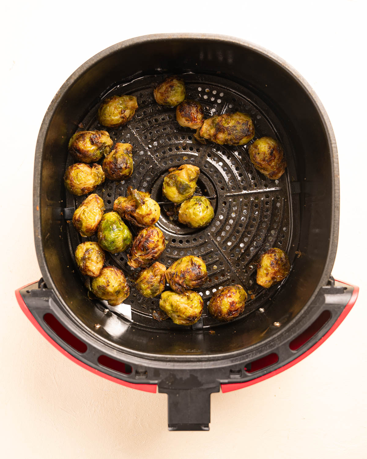 Golden Brown Air Fryer Brussels Sprouts in a red Air Fryer Basket. 