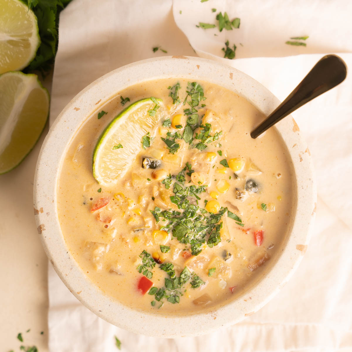Corn Soup top down image with spoon and a lime garnish with a sprinkling of fresh cilantro