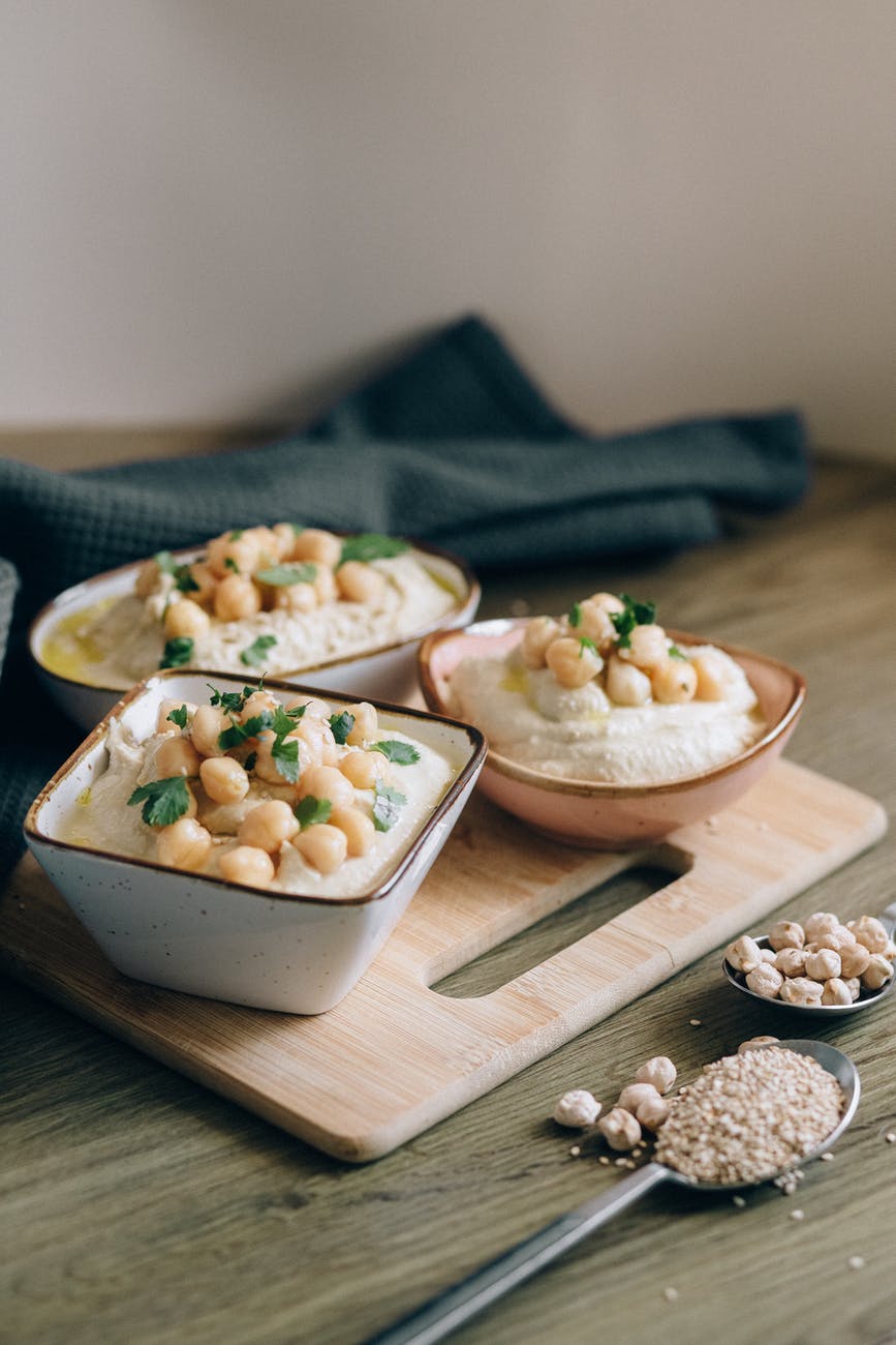 Tofu Hummus in 3 small bowls topped with chickpeas and herbs. 
