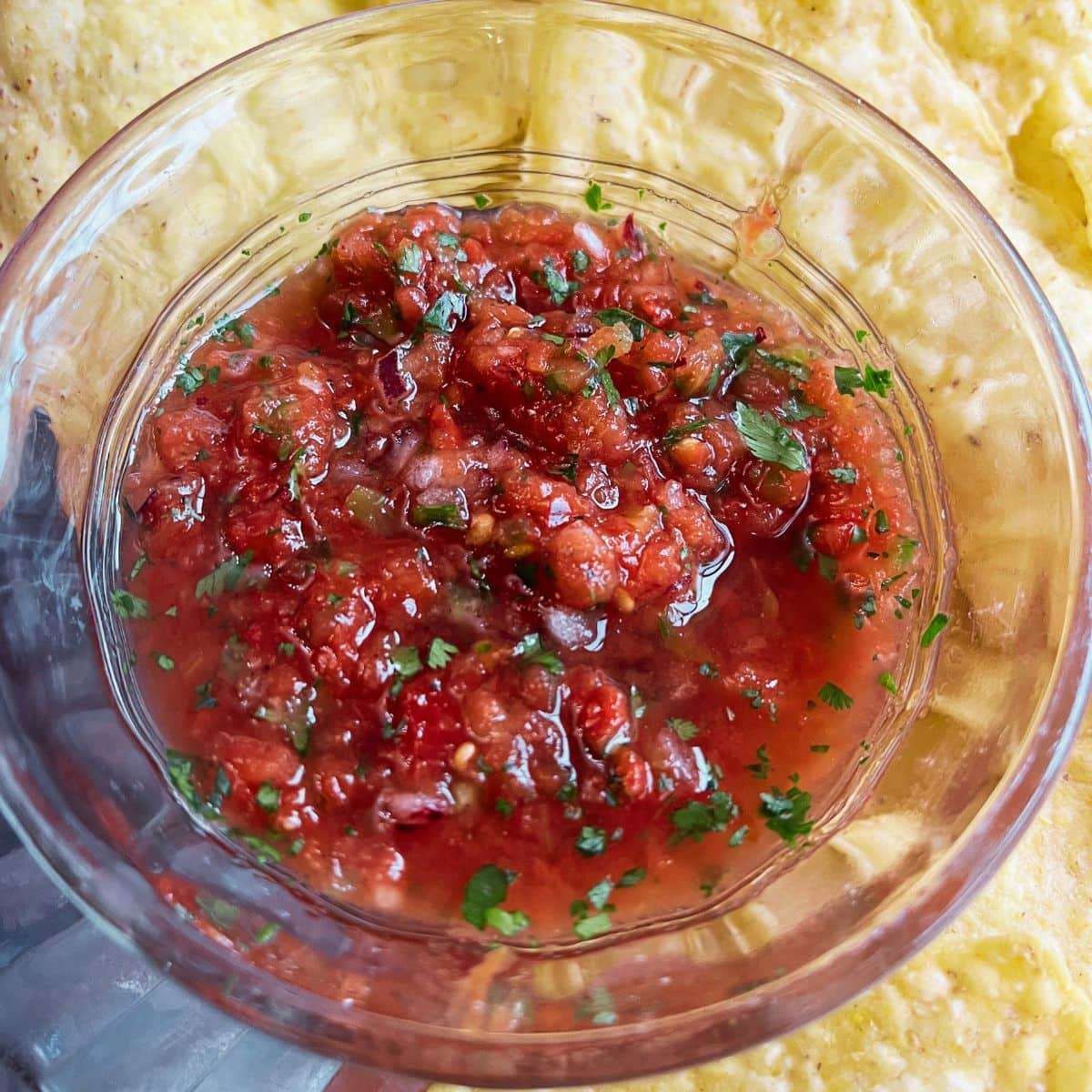 Red Low Sodium salsa in a glass ramakin with bits of fresh herbs distributed throughout the salsa. 