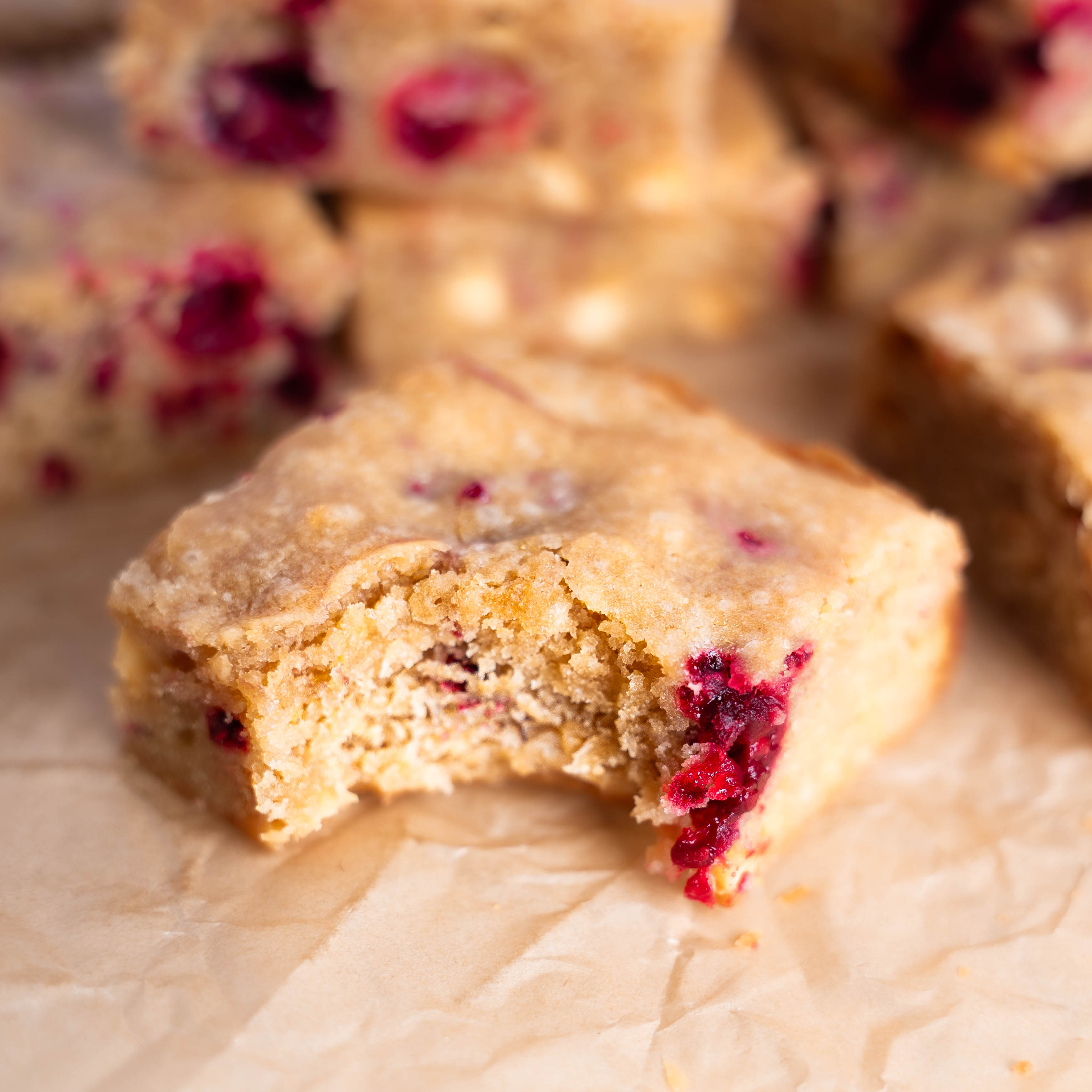 a close up of a blondie with a bite take from it and raspberry showing in the corner of the bite. 