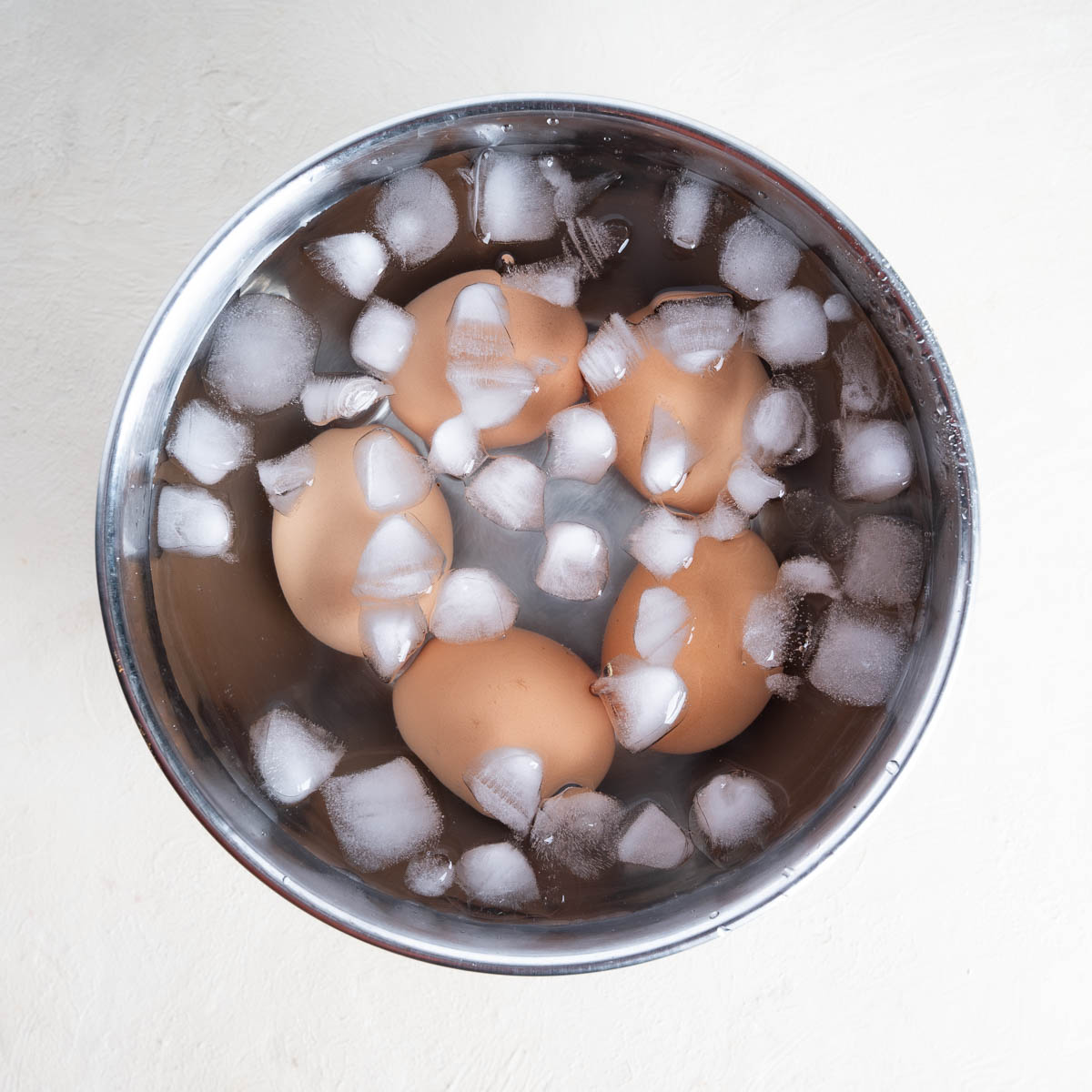 Eggs in an ice bath in a large silver bowl. 