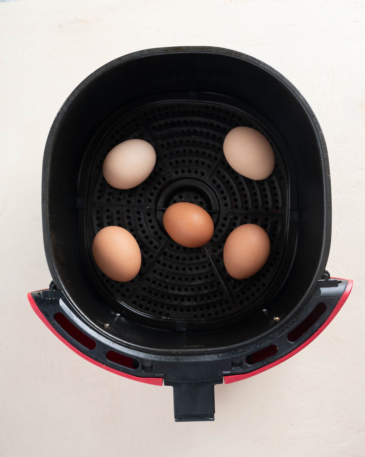 Eggs in a red air fryer basket