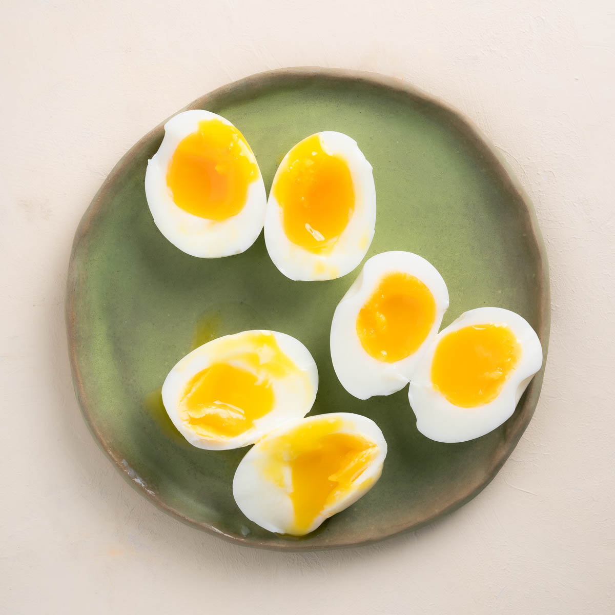 Three Air Fryer Soft Boiled Eggs sliced in half and displayed on on a sage green plate