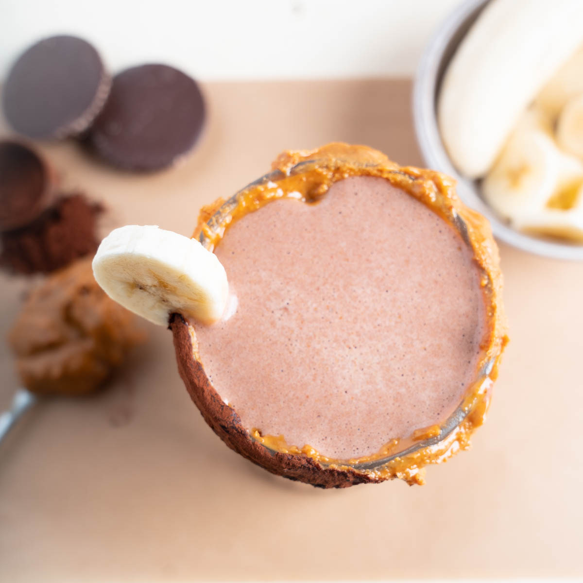 Dark Brown Peanut Butter Chocolate Smoothie with peanut butter cocoa powder rim. The props show the healthy ingredients used in the smoothie