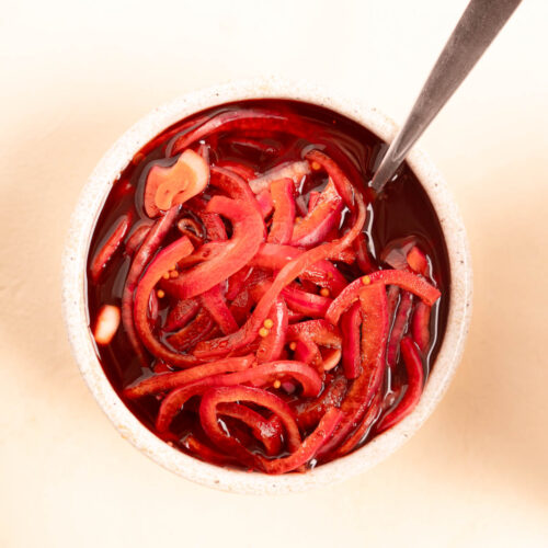 Red tinted Balsamic Pickled Onions with a spoon in a white bowl