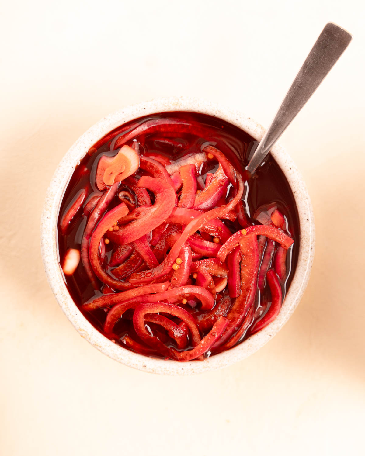 Red tinted Balsamic Pickled Onions with a spoon in a white bowl
