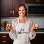 Ann Kent From Peas and Hoppiness holding an avocado and wearing a chefs apron