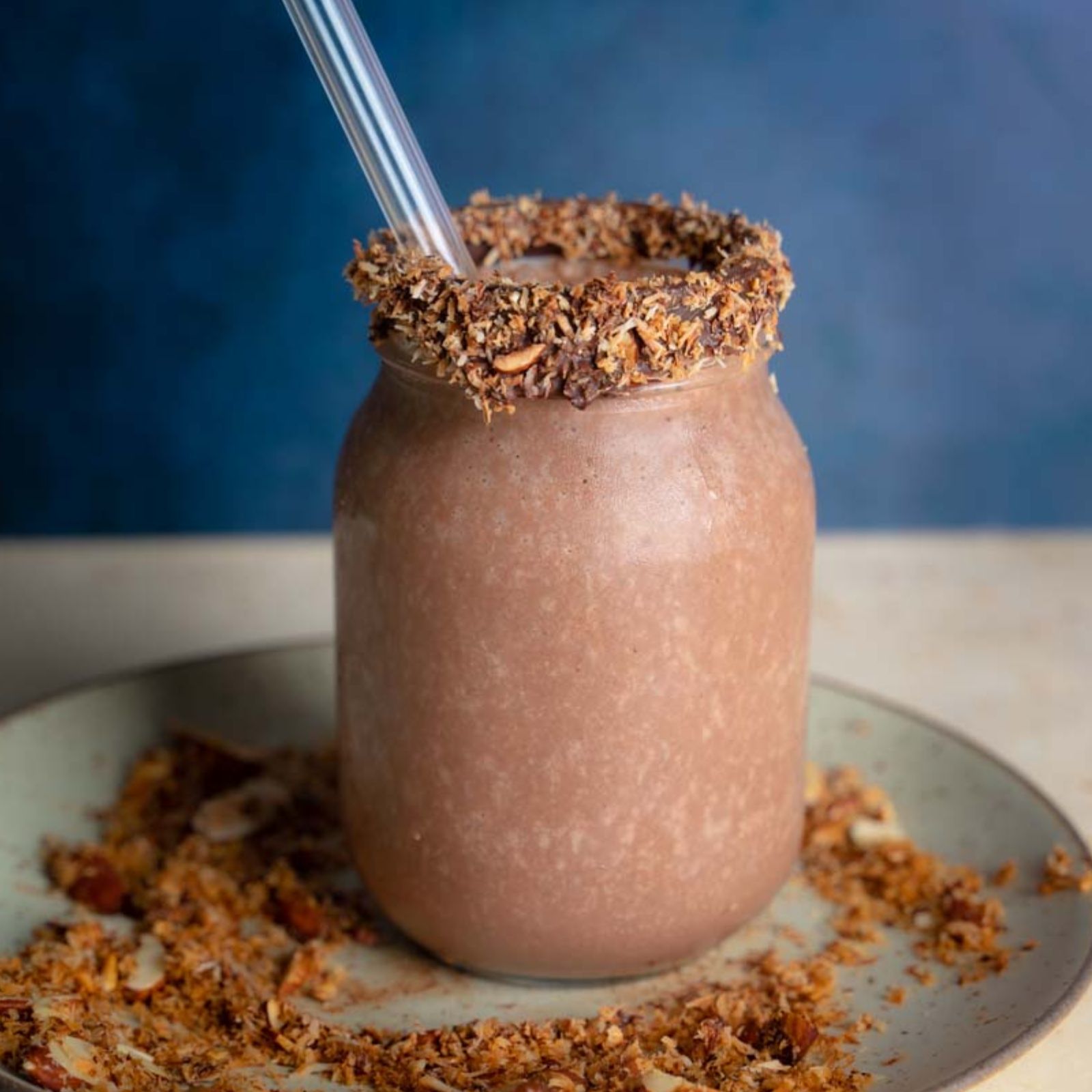 Deep brown smoothie on a plate with toasted nuts
