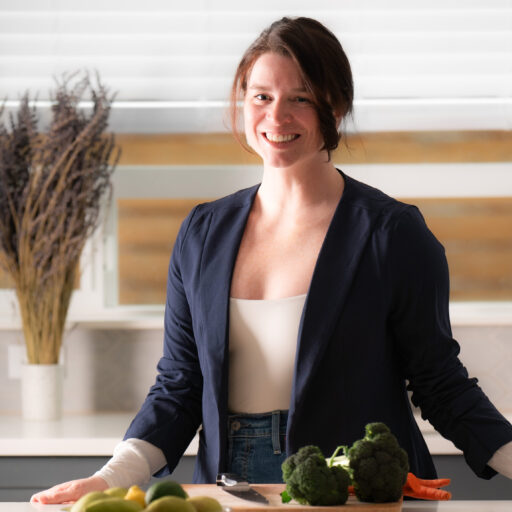 Sarah Harper in her kitchen with a cutting board, broccoli, carrots, and a fruit bowl.