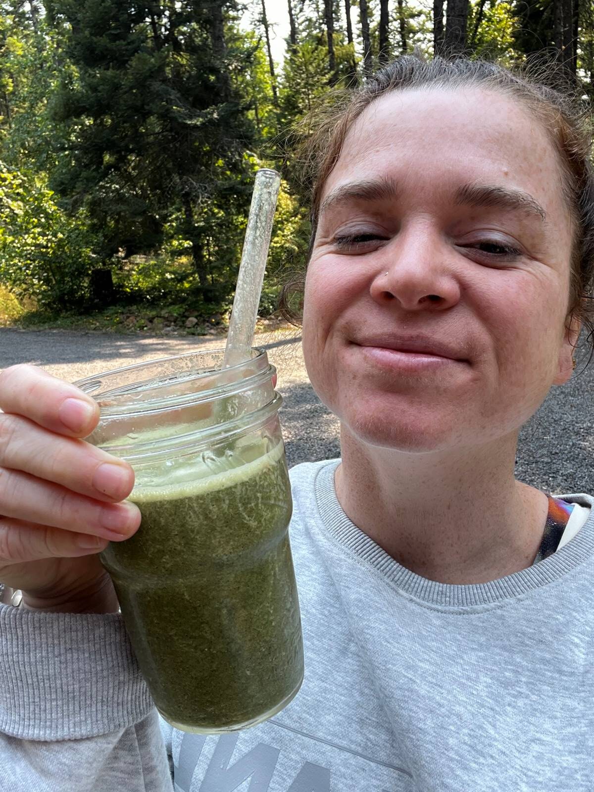 Dietitian Sarah with a copycat panera green smoothie in a mason jar with a glass straw.