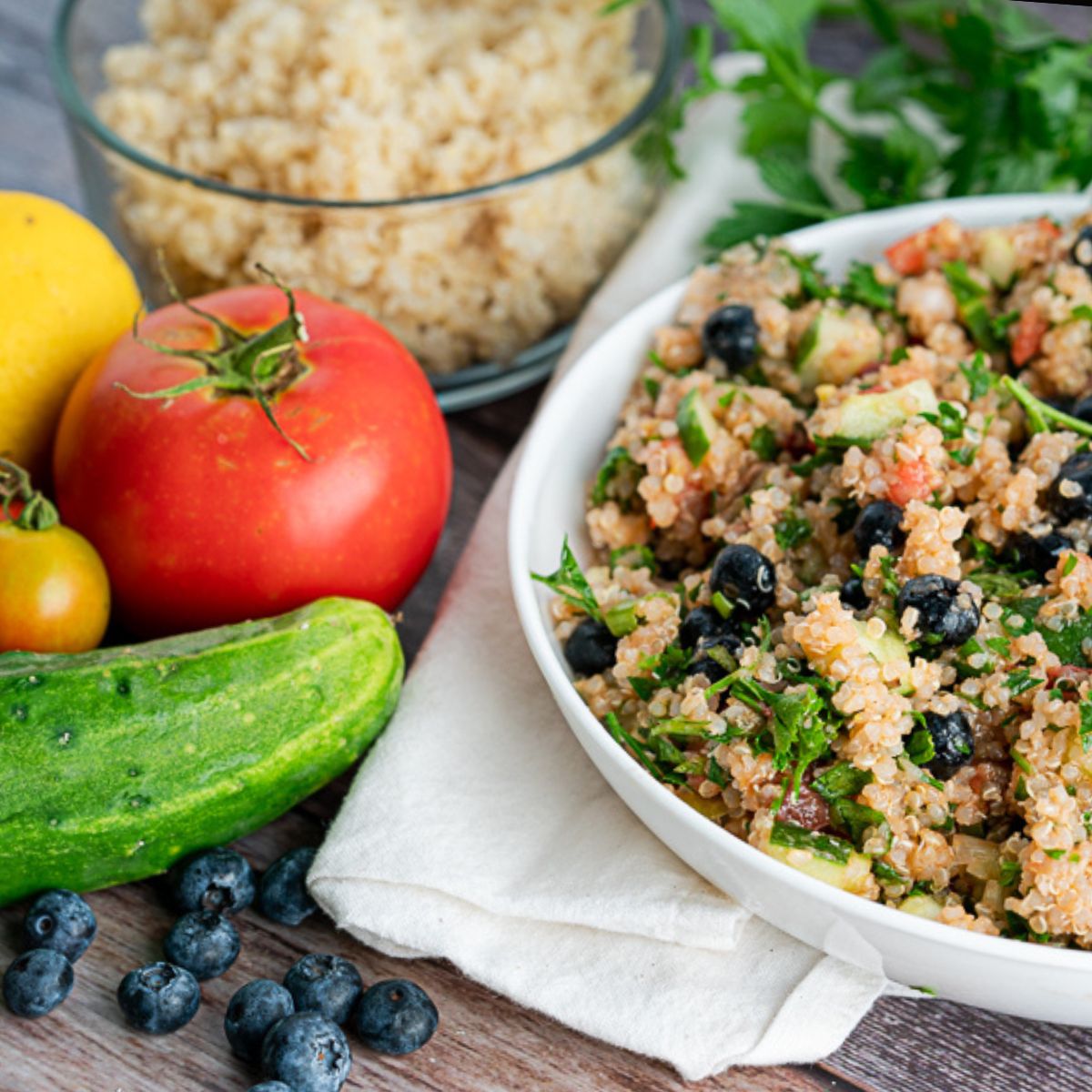 ingredients in vegetable quinoa recipe including blueberries, cucumber, tomato, lemon, parsley, and quinoa