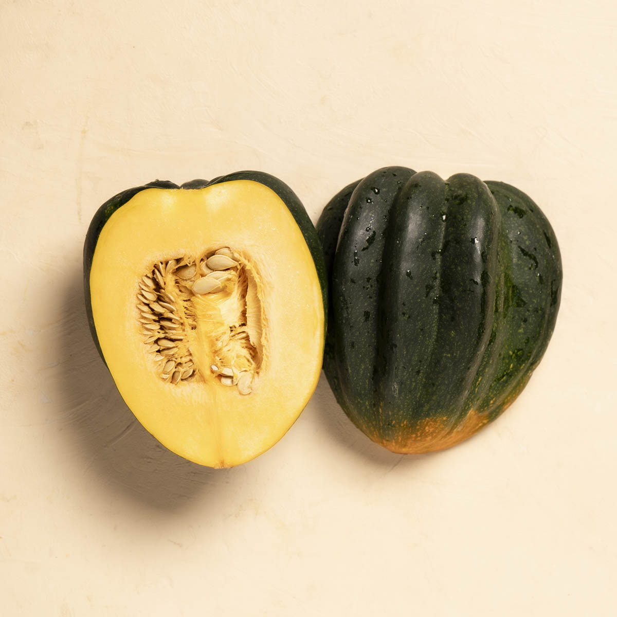 halved acorn squash with seeds on a off white backdrop