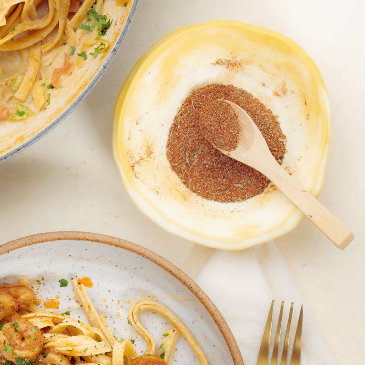 Cajun Seasoning in a yellow small bowl with a wooden spoon