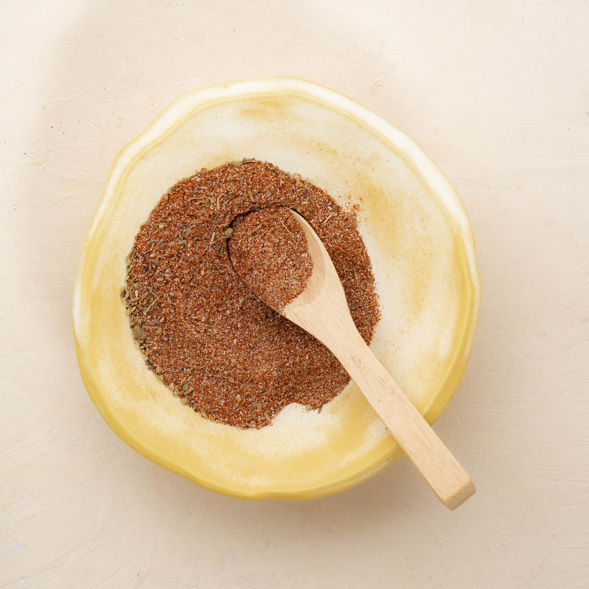 cajun seasoning in a small bowl with a light brown wooden spoon