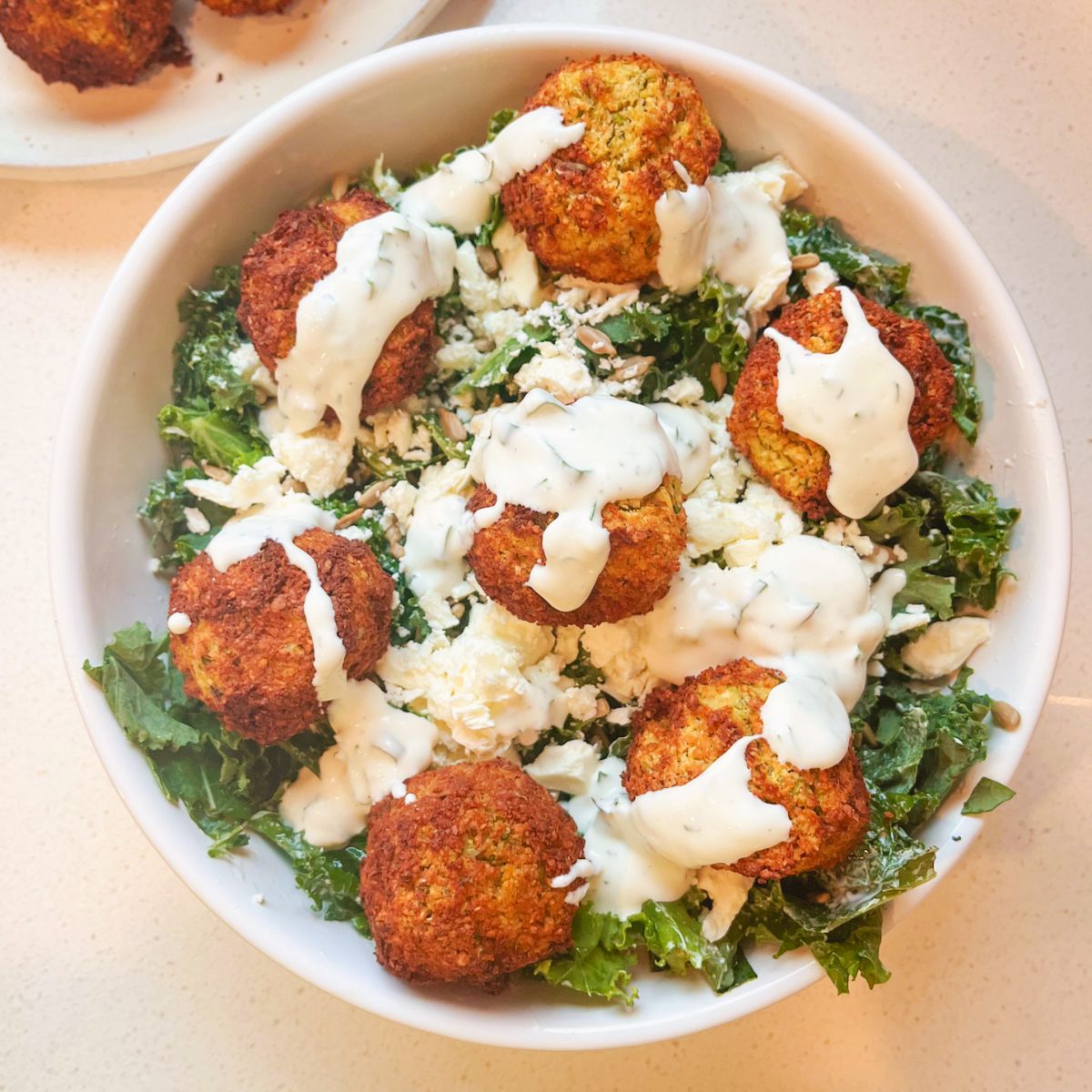 falafel salad in a white bowl with creamy yogurt dressing