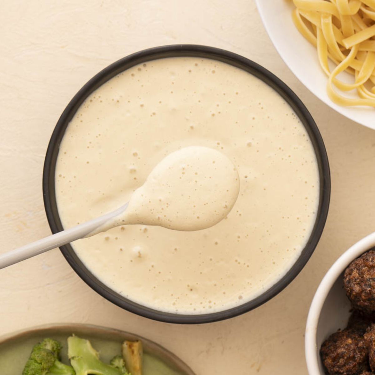 vegan cashew alfredo sauce in a black bowl with a spoon