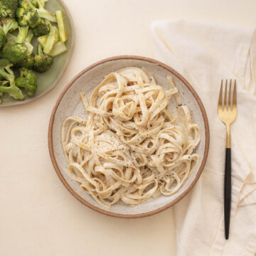 a bowl of fettuccine alfredo with a side of brocoli